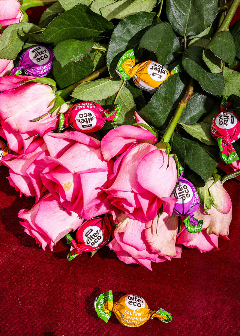 Bouquet of pink roses with wrapped candies on a red surface
