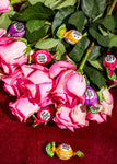 Bouquet of pink roses with wrapped candies on a red surface